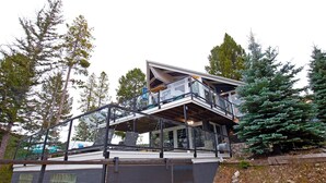 Een modern huis met een glazen balkon, omringd door bomen.