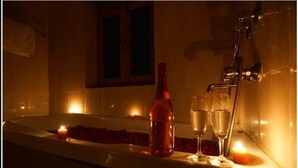Eine Badewanne mit Rosenblättern, Kerzen und Champagnergläsern.