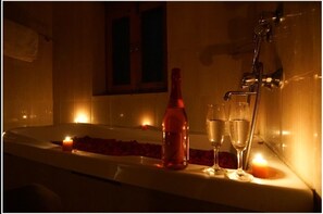 Relax in a serene bathroom with a bathtub, champagne, and candlelight.