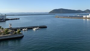 Een jachthaven met aan wal liggende boten, een heldere lucht en heuvels in de verte.