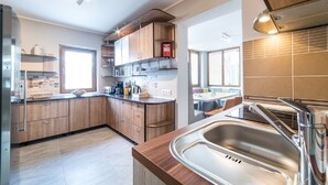 A modern kitchen with wooden cabinets, a stainless steel sink, and a window providing natural light. - Holiday home with heated outdoor swimming pool up to 12 persons (Cluj-Napoca)