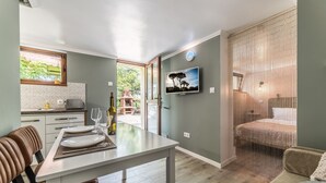 A modern kitchen with a dining area, a TV mounted on the wall, and a view of the outdoors. - Holiday home with heated outdoor swimming pool up to 12 persons (Cluj-Napoca)