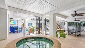 Une piscine intérieure avec un bord carrelé, un ventilateur de plafond et un espace détente avec des chaises.