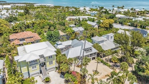 Vue aérienne d’une zone résidentielle côtière, avec des maisons, des palmiers et une plage.