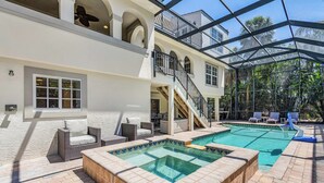Un área de piscina con hidromasaje, mobiliario exterior y un patio cubierto.