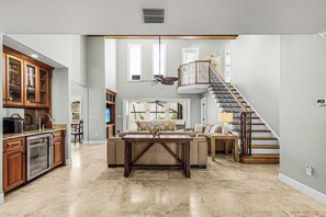 Amplia sala de estar con cocina, mesa de comedor, sofá y escalera.