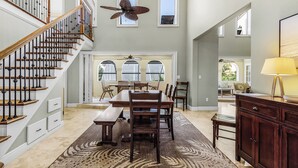Un interior amplio con escaleras, comedor y ventilador de techo.