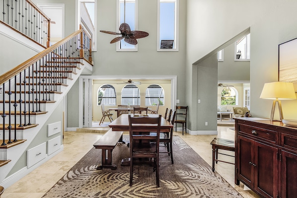 A spacious interior with a staircase, dining area, and a ceiling fan.
