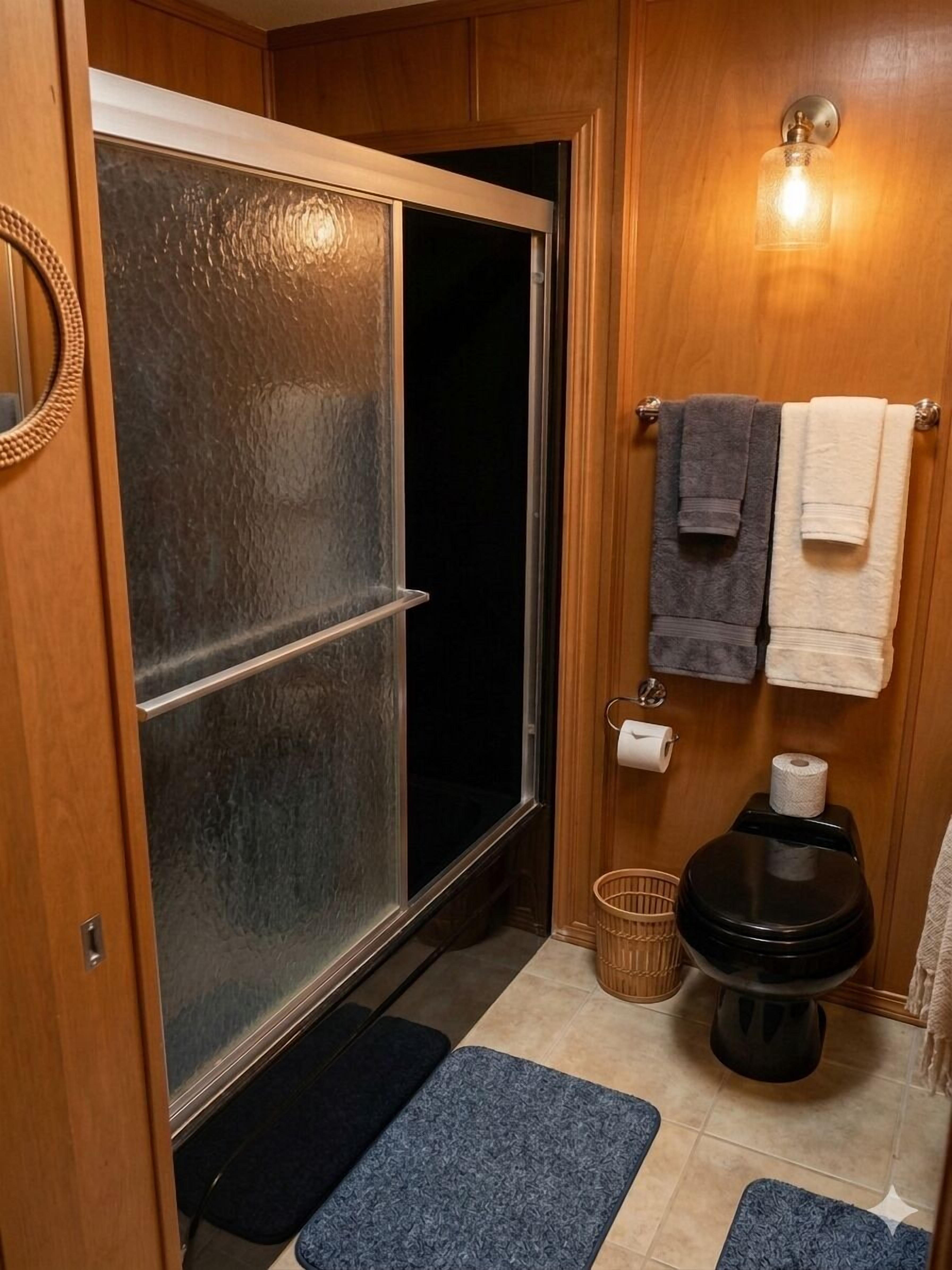 A compact bathroom with a shower, toilet, and towel rack.