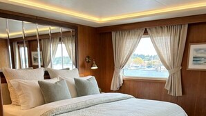 Un dormitorio con cama, cortinas, alfombra y vista al exterior.