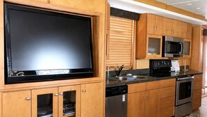 Una cocina con armarios de madera, un televisor de pantalla plana grande, un microondas y un lavavajillas.