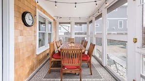 A covered patio with a wooden table and chairs, a clock on the wall, and a view of the backyard. - Quintessential New England Home on Private Beach  (Westerly)