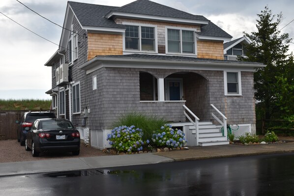 A two-story house with a front porch, a garage, and a driveway. - Quintessential New England Home on Private Beach (Westerly)