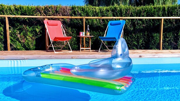 En swimmingpool med oppustelige legetøj og liggestole.