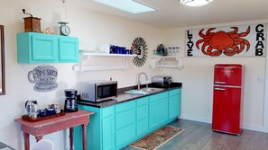 Una cocina compacta con armarios color turquesa, un refrigerador rojo, un microondas y una cafetera.