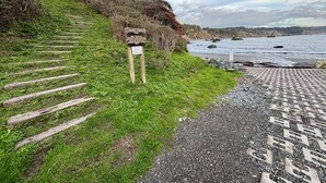 Una escalera de madera que conduce a un área pavimentada con un letrero que indica un sendero.