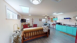 Una habitación con cama, mesa de comedor, zona de cocina y televisor.