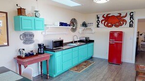 Una cocina compacta con gabinetes verde mar, un refrigerador rojo, un microondas y una cafetera.