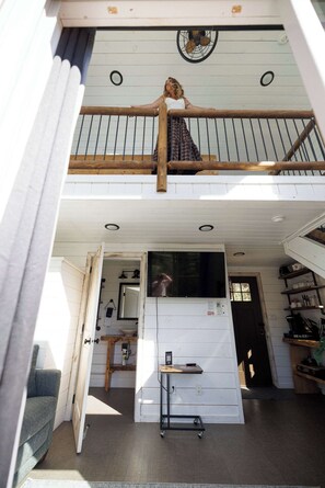 A two-story house with a balcony, a kitchen with a refrigerator, and a dining area.