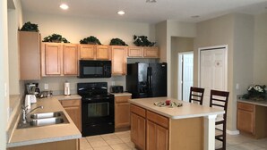 A modern kitchen with wooden cabinets, a black stove, a microwave, and a refrigerator.