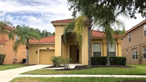 A residential building with a yellow facade, red-tiled roof, and a front entrance.