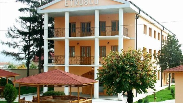 A building with the name "ETRUSCO" on the facade, featuring a multi-story structure with balconies and a covered outdoor seating area. - Hotel Etrusco (Gherla)