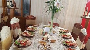 A round dining table set for a meal with various dishes, glasses, and a centerpiece. - Hotel Etrusco (Gherla)
