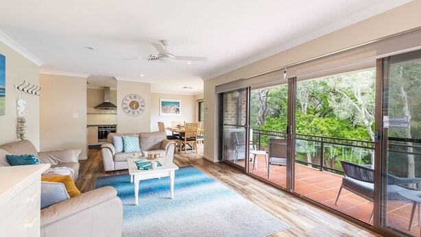 A spacious living room with a large sliding glass door leading to an outdoor balcony with a view of trees. - Bay Parklands, 49 2 Gowrie Ave - ducted aircon, Wifi, views, pool, tennis (Nelson Bay)