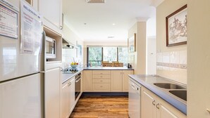A modern kitchen with white cabinets, a built-in oven, and a large window. - Bay Parklands, 49 2 Gowrie Ave - ducted aircon, Wifi, views, pool, tennis (Nelson Bay)