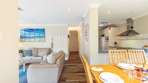 A modern living room with a sofa and a dining table set for a meal. - Bay Parklands, 49 2 Gowrie Ave - ducted aircon, Wifi, views, pool, tennis (Nelson Bay)