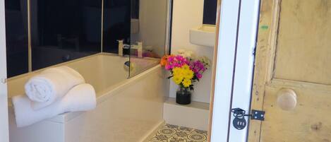 A bathroom with a bathtub, a toilet, a sink, and a mirror.
