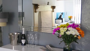 A hotel room counter with a bottle of wine, glasses, a vase of flowers, and a newspaper. - Westeria Cottage (Barnstaple)