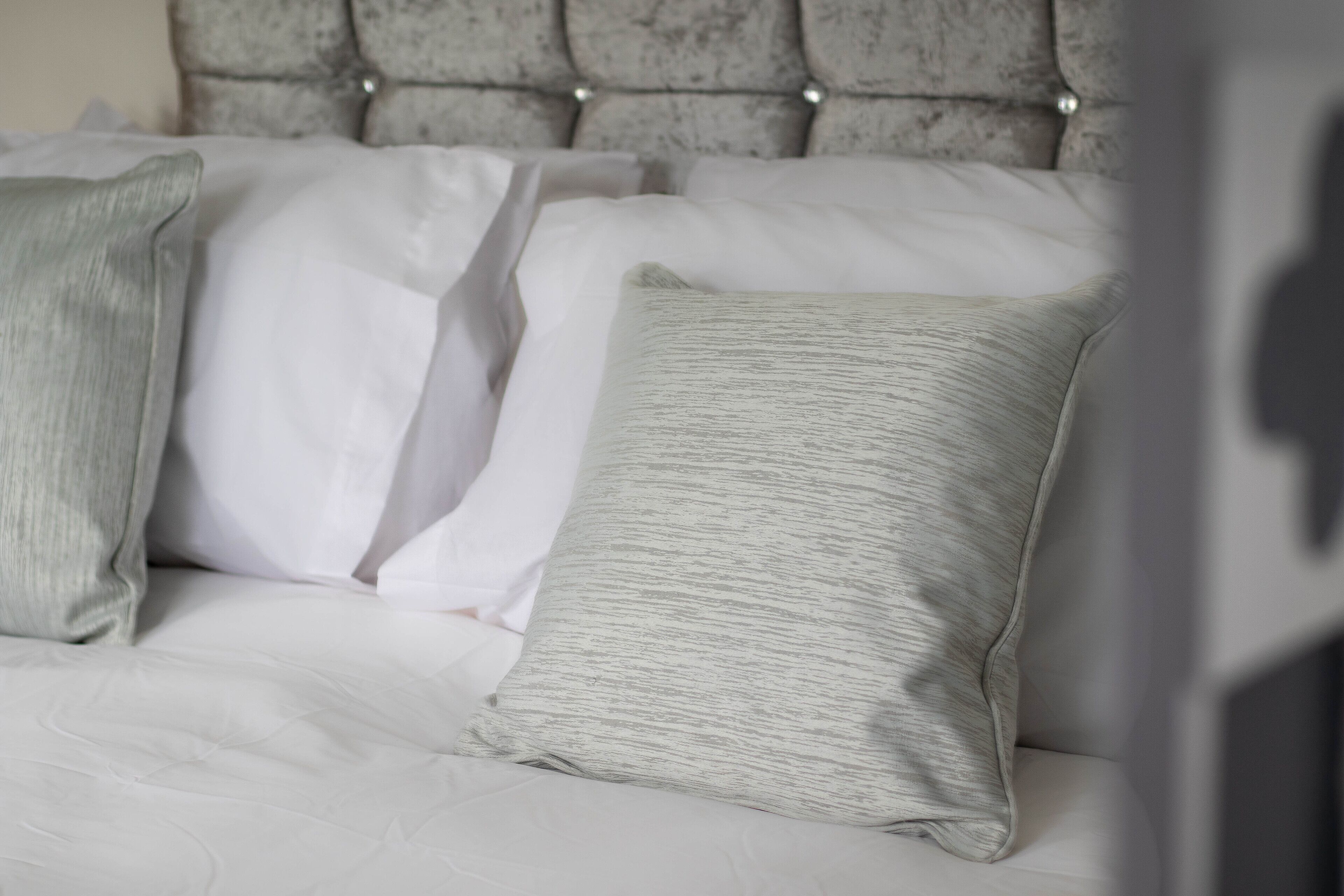A bed with a tufted headboard and multiple pillows.