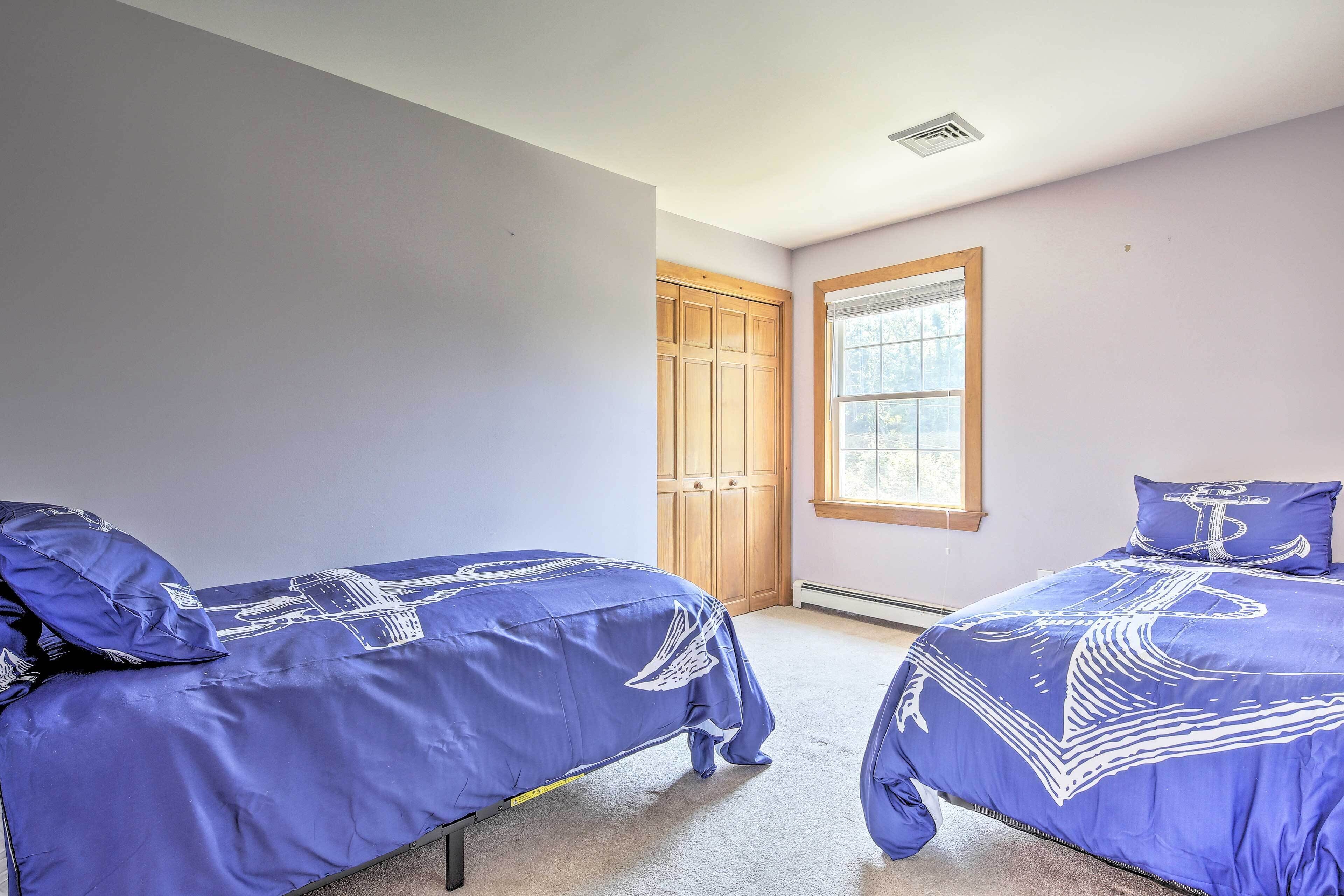A bedroom with two beds, a window, and a wooden door.