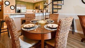 A dining area with a round table, wicker chairs, and a spiral staircase in the background. - Aldea A8 Beachfront 2 Bedroom 2 Bath - Tranquil Belleair Beach (Belleair Beach)