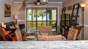 A living room with a marble countertop, wicker furniture, a ceiling fan, and a television. - Aldea A8 Beachfront 2 Bedroom 2 Bath - Tranquil Belleair Beach (Belleair Beach)