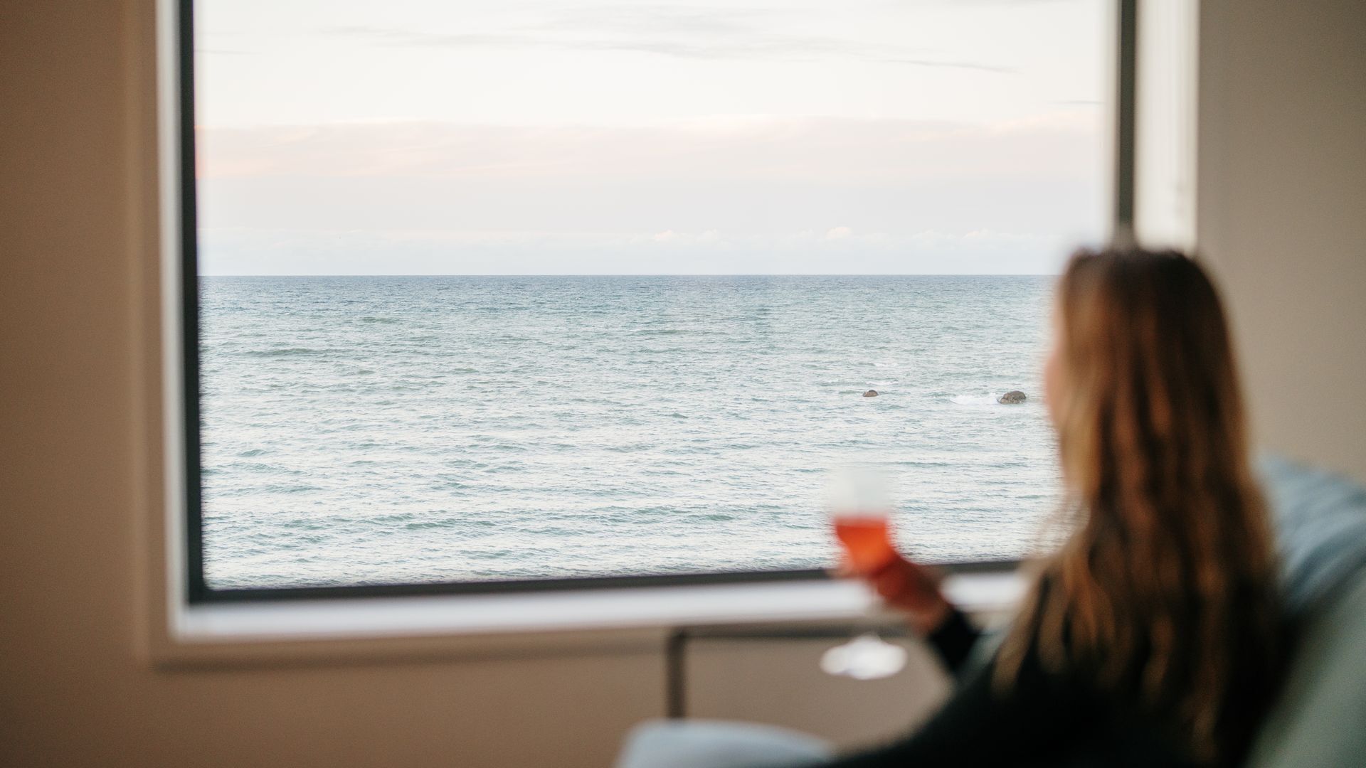 Une pièce avec vue sur la mer, visible par une fenêtre.
