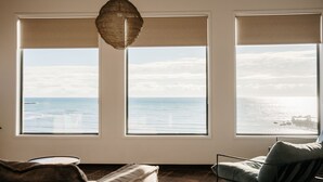 A room with three large windows offering a view of the sea. - Absolute waterfront beauty in Tasmania (Penguin)