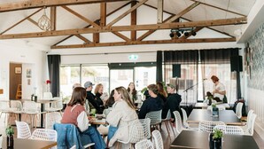A restaurant with a high wooden ceiling, white wicker chairs, and tables. - Absolute waterfront beauty in Tasmania (Penguin)