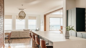 A modern kitchen with a large island, bar stools, and a view of the ocean. - Absolute waterfront beauty in Tasmania (Penguin)