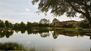 A calm lake with a grassy bank and a building in the background. - Fantastic house next to Disney. Enjoy private heated pool! (Kissimmee)