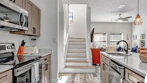 A modern kitchen with a central staircase, stainless steel appliances, and a minimalist design. - Fantastic house next to Disney. Enjoy private heated pool! (Kissimmee)