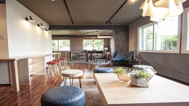 A modern interior with a wooden floor, a bar area, seating, and large windows. - UCHI Living Stay Otaru Suitengu (Otaru)