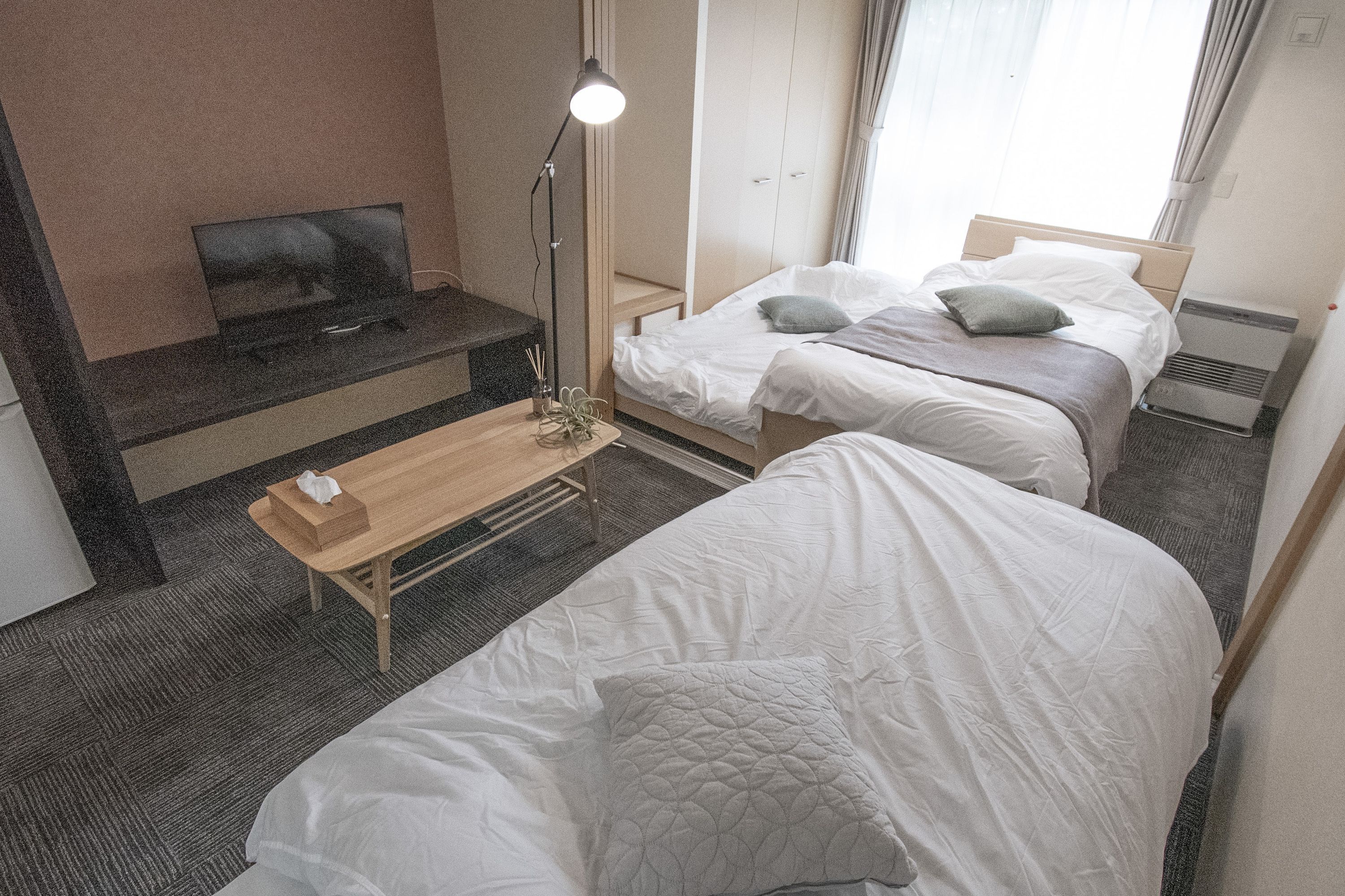 Een hotelkamer met twee bedden, een televisie, een bureau en een lamp.
