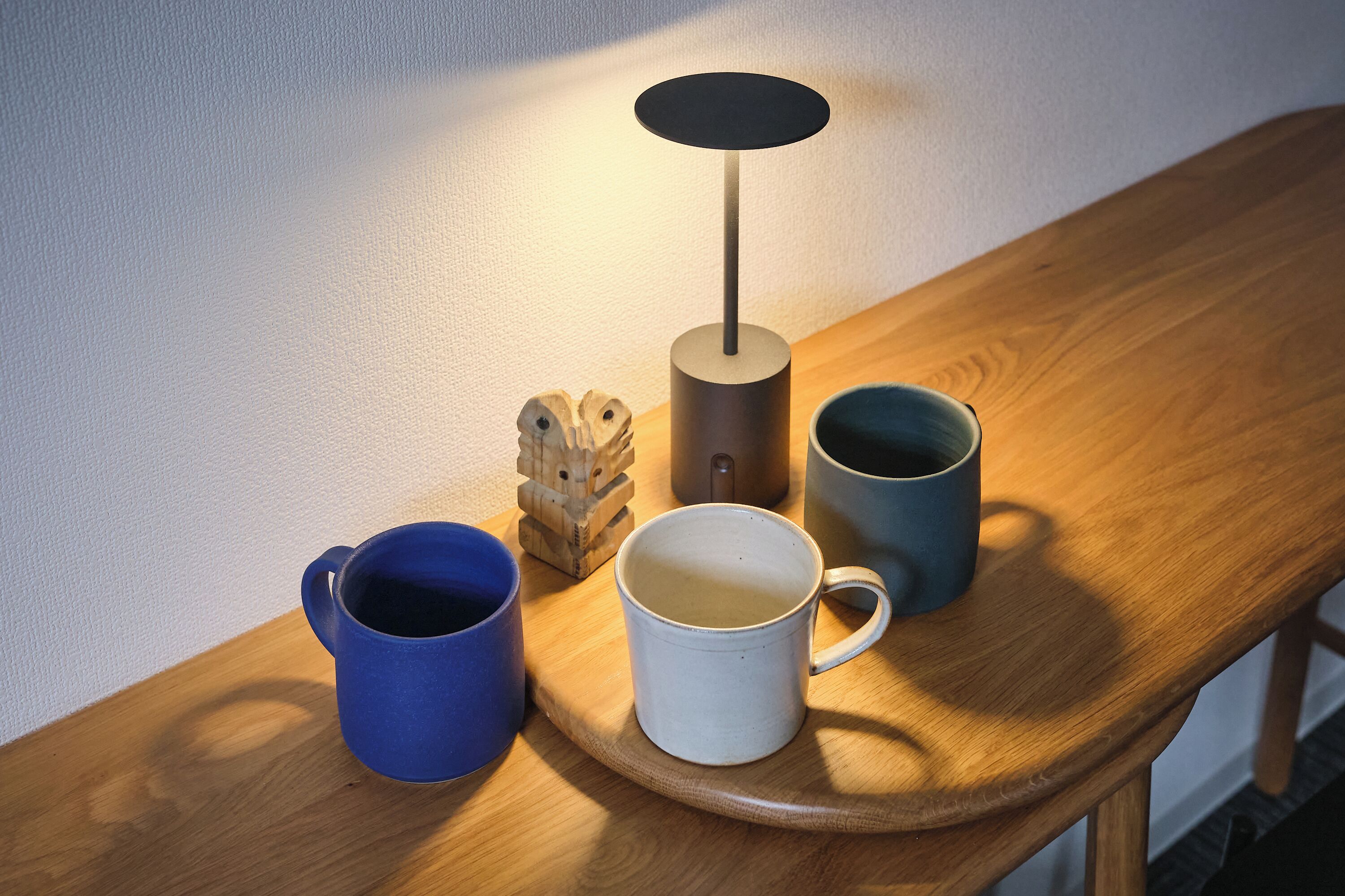 Uma mesa de madeira com três canecas e uma prensa de café.
