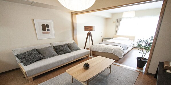 Una habitación de hotel moderna con sofá, una mesita, una lámpara y una cama.