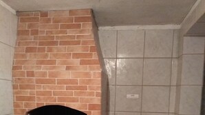 Una cocina con horno de ladrillo, un lavabo y una pileta roja.