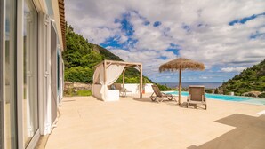 A covered outdoor seating area with a pool, a pergola, and a view of the sea. - Casa do Outeiro in a rural area (Povoação)