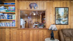 Un interior de madera con una estantería, una figura de oso sobre una mesa y un cuadro en la pared.
