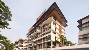 Un immeuble résidentiel à plusieurs étages, doté de balcons, d’une entrée couverte et surplombant un ciel dégagé.